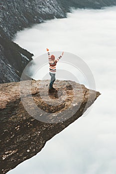 Woman happy raised hands on Trolltunga rocky cliff