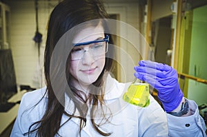 Woman happy scientist holding and paying attention skillful yellow chemical reaction in chemistry laboratory for science