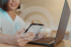 Woman happy and smile while using laptop or smartphone to work study on work desk with clean nature background background.