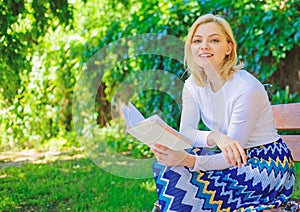 Woman happy smiling blonde take break relaxing in garden reading poetry. Girl sit bench relaxing with book, green nature