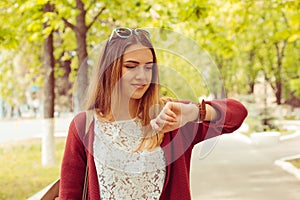 Woman happy smiling looking at wristwatch isolated on green park background