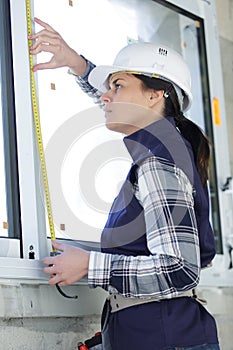 woman in hard hat measuring window