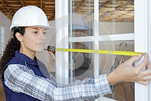 woman in hard hat measuring window