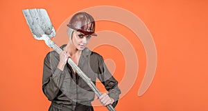 woman hard worker in protective helmet and boilersuit hold shovel, copy space, 1 may