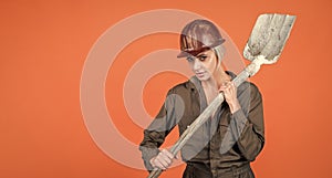 woman hard worker in protective helmet and boilersuit hold shovel, copy space, 1 may