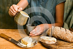 Woman has breakfast adds milk to coffee