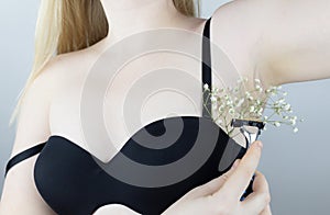 A woman has flowers sticking out under her armpits, symbolizing grown hair. Concept photo. Body positivity and body acceptance.