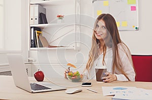 Woman has healthy business lunch in modern office interior