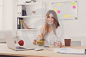 Woman has healthy business lunch in modern office interior