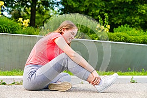 A woman has injured her ankle during sports and holds it tight