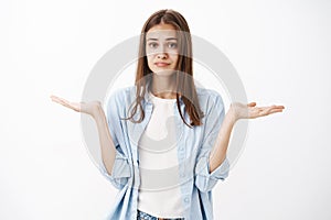 Woman has no clue what do. Unaware and clueless attractive feminine girl with brown hair in blue blouse over white t