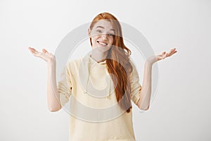 Woman has no idea, nothing to tell. Shrugging unaware attractive female with ginger hair, standing with spread palms and