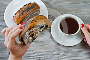 Woman has snack at work, eats roll with poppy seeds and drinks t