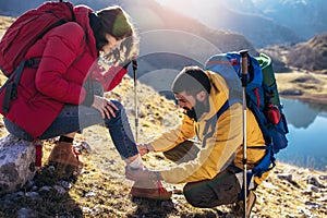 A woman has sprained her ankle while hiking, her friend uses the first aid kit