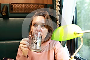 Woman has tea in train compartment