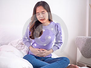 A woman has an upset stomach, tense with a hand by pressing the stomach. Menstrual cramps