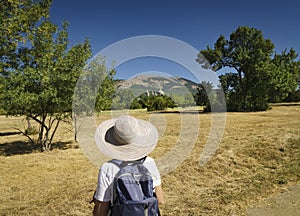 Woman with hat and backpack looking at a landscape.