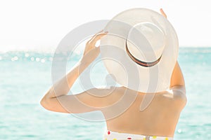 Woman with hat on the beach enjoying summer vacation