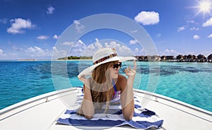 A woman with hat enjoys her summer vacation time with a sunbath on a luxury yacht