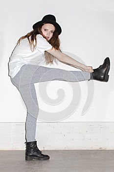 Woman in hat holding leg up and looking at camera