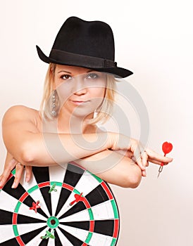 Woman in hat holds board for darts on white