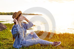 Woman in hat and jeans sits on the background of the sea