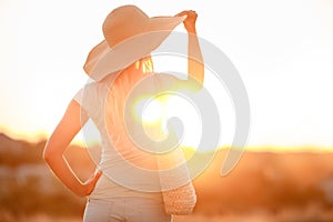 Woman in hat with large fields, at sunset