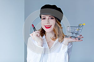 Woman in hat with lipstick for makeup and shopping cart