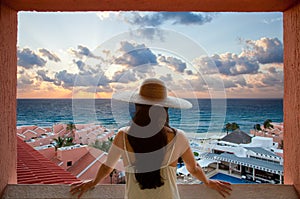 Woman with hat looking at the beach and sky