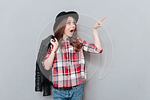 Woman in hat and plaid shirt pointing finger away