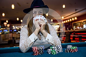 Woman in hat with playing cards and poker chips in casino