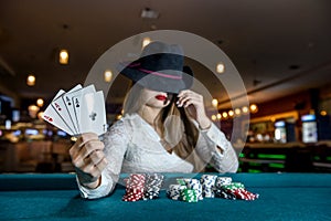 Woman in hat with playing cards and poker chips in casino