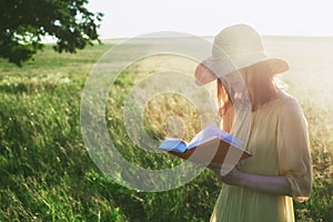 Woman in hat reading book in sunlight