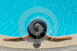 Woman in hat relaxing at the pool