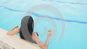 Woman in hat relaxing at pool with cosmopolitan cocktail