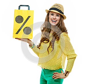 Woman in hat showing shopping bag symbolising beginning of sales