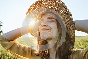 Woman with hat smiling and enjoying summer sunlght in meadow