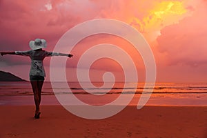 Woman in hat standing on wet sand on beach