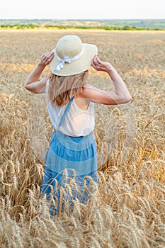 Woman with hat in summer field golden wheat, freedom concept. Happy girl enjoying life, colorful field with ripe