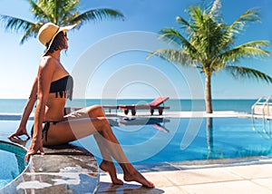 Woman in hat sunbathe near sear and swimming pool