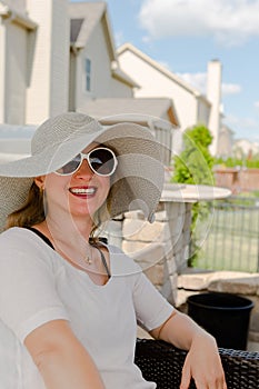 Woman in Hat and Sunglasses Sitting on Patio