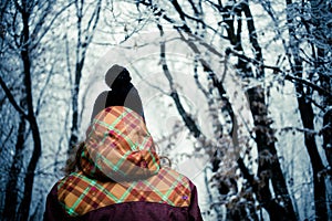 woman with hat walking in frost covered forest in winter