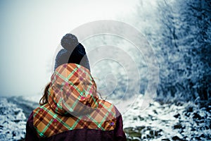 woman with hat walking in frost covered forest in winter