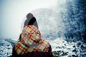 woman with hat walking in frost covered forest in winter