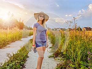 Woman in the hat walking on summer field
