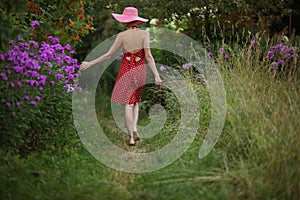 Woman in a hat walks among the flowers