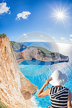 Woman with hat watching Navagio beach with shipwreck on Zakynthos island in Greece