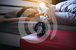 Woman hates getting stressed waking up early morning,Female stretching her hand to ringing alarm to turn off alarm clock