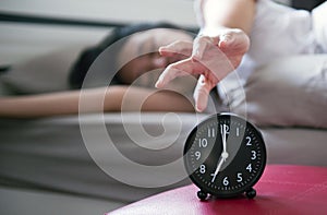 Woman hates getting stressed waking up early morning,Female stretching her hand to ringing alarm to turn off alarm clock in bedroo