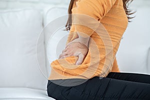 Woman have a back and hip pain sitting on bed in bedroom